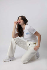 Chica agachada con un top y unos jeans blancos